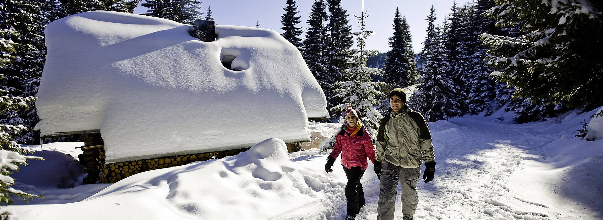 Winterwandern vor der tiefverschneiten Hütte